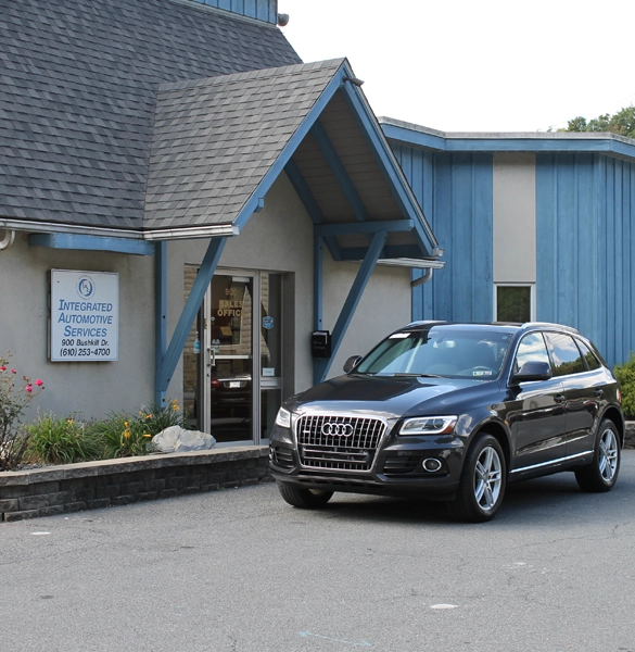 Black Audi SUV parked outside "Integrated Automotive Services" building with blue accents and glass door.